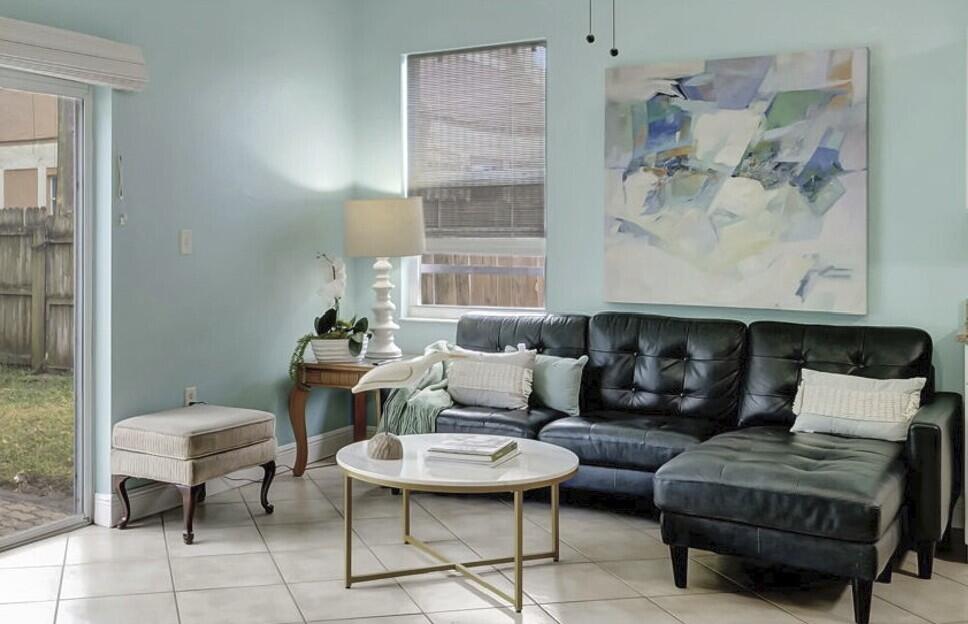 A living room with light blue walls, a black leather sectional, and a round coffee table — 1616 S Johnson Street, FL 33460, FL