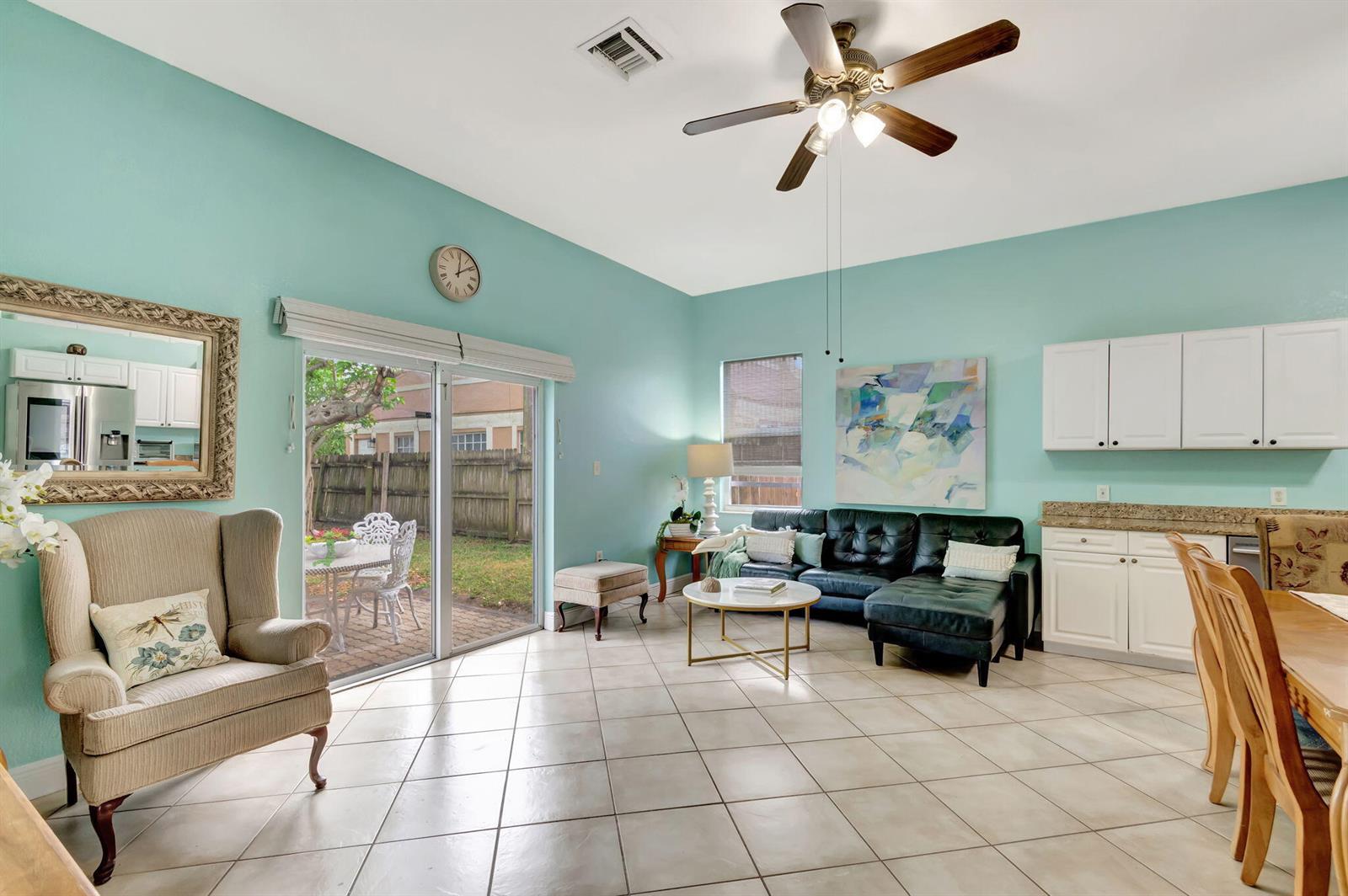 A living room with light blue walls, tile flooring, a ceiling fan, and a sliding door — 1616 S Johnson Street, FL 33460, FL