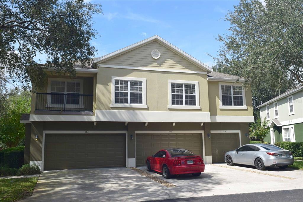 A two-story residential building features three garage doors and a balcony under a gabled roof — 874 ASHWORTH OVERLOOK DRIVE, APOPKA, FL