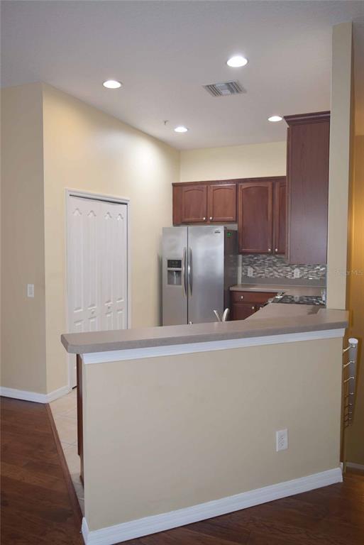 A kitchen with wood cabinets, stainless steel appliances, and a breakfast bar overlooking the room — 874 ASHWORTH OVERLOOK DRIVE, APOPKA, FL