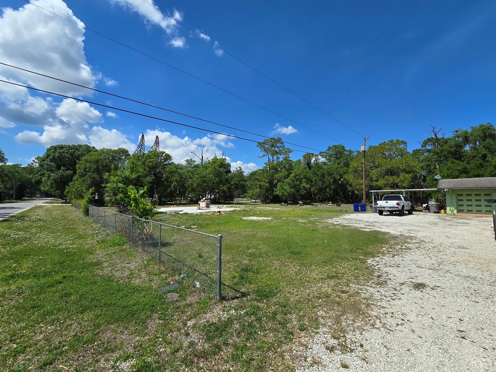 A gravel driveway leads to a vacant lot with a concrete slab and chain-link fence — 144 N Elm Street, Fellsmere FL 32948, FELLSMERE, FL