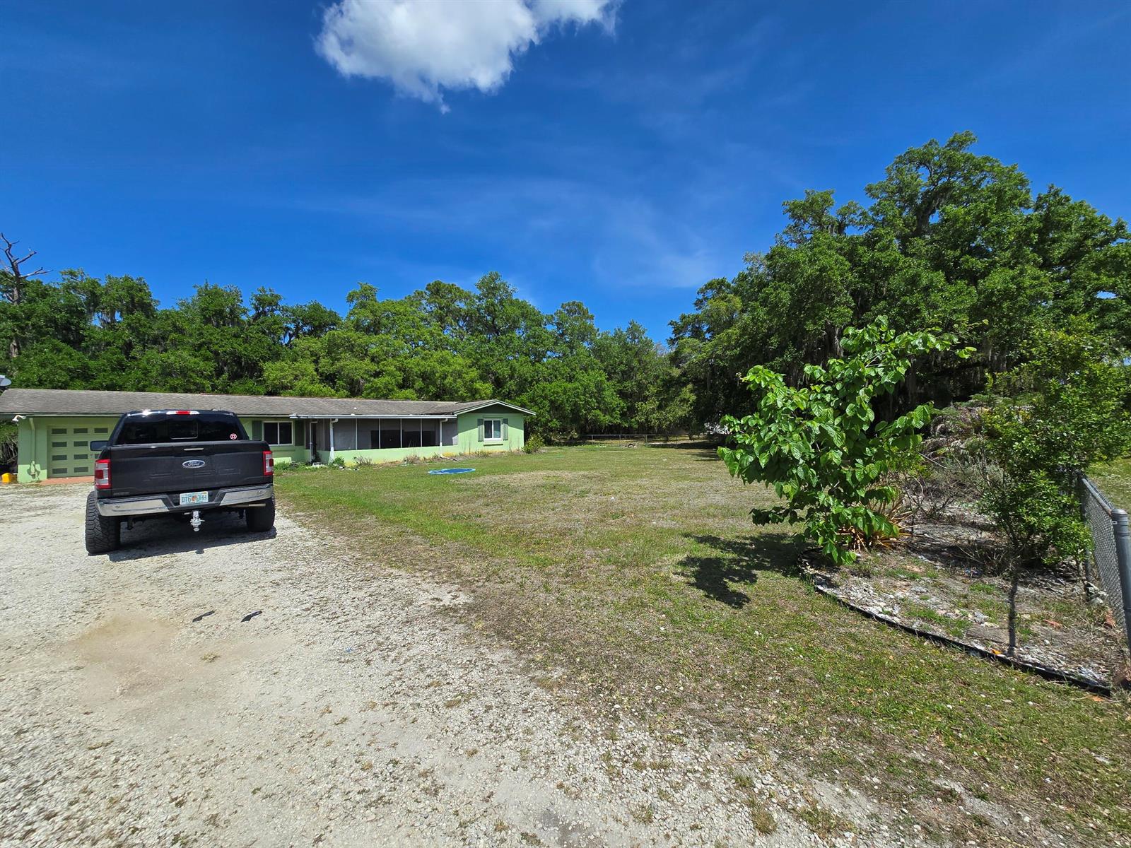 A black pickup truck is parked on a gravel driveway in front of a house — 144 N Elm Street, Fellsmere FL 32948, FELLSMERE, FL