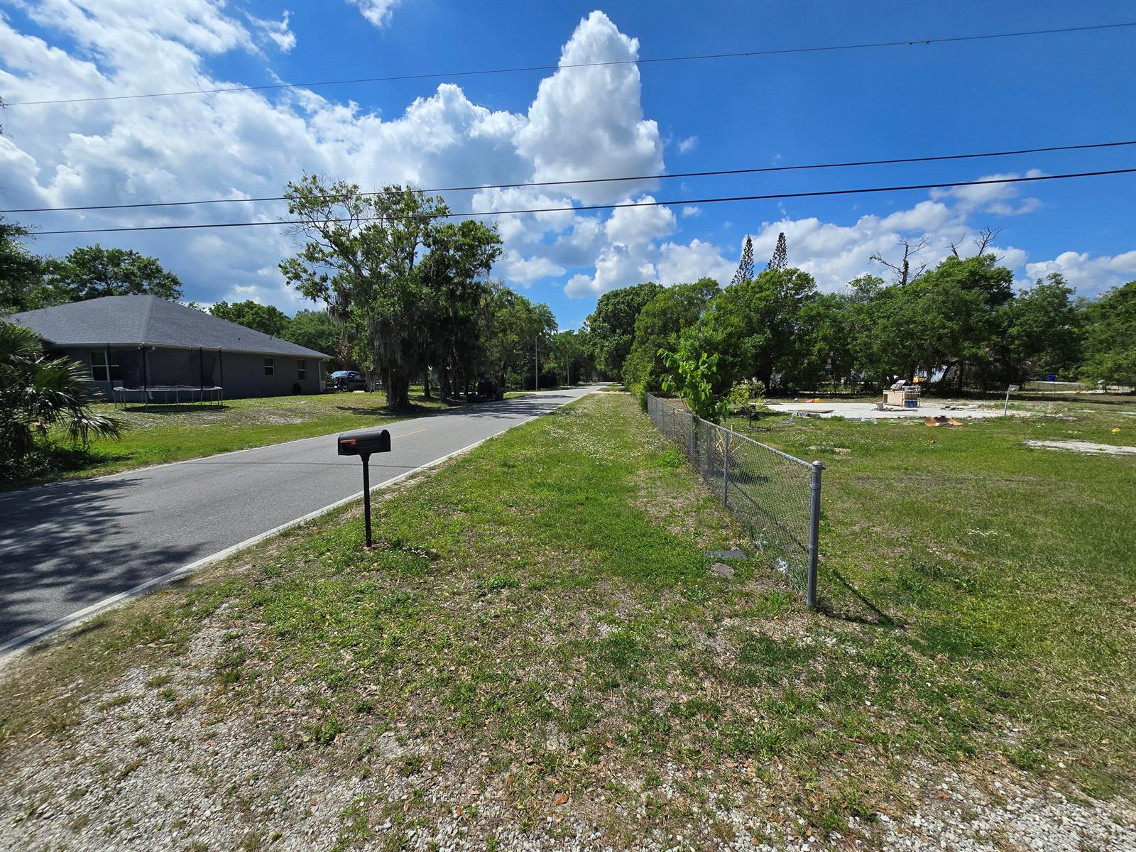 A paved road runs past a residential lot with a chain-link fence and mailbox — 144 N Elm Street, Fellsmere FL 32948, FELLSMERE, FL