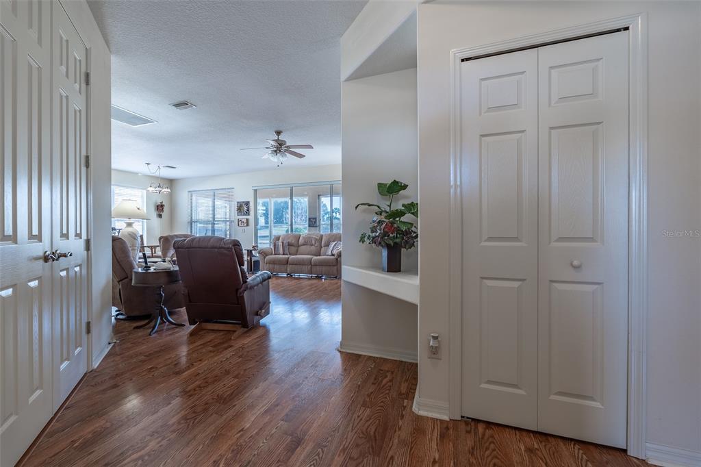 A view from a hallway looking into a living room with wood-look flooring — 15803 SW 11TH COURT ROAD, OCALA, FL