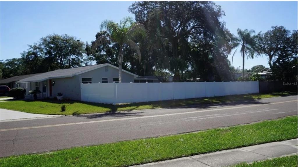 A single-story house with a white vinyl privacy fence and palm trees in the yard — 8518 WOODLAKE DRIVE, TAMPA, FL