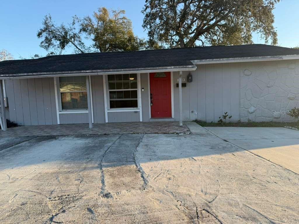 A single-story house with a grey exterior, a red front door, and a paved driveway — 8518 WOODLAKE DRIVE, TAMPA, FL