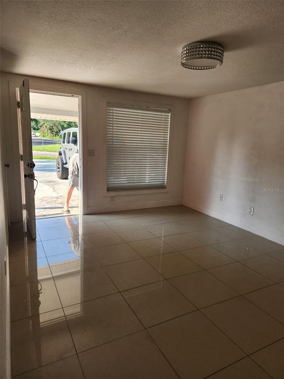 An interior room features light-colored tile flooring, a window with blinds, and an open doorway — 8518 WOODLAKE DRIVE, TAMPA, FL
