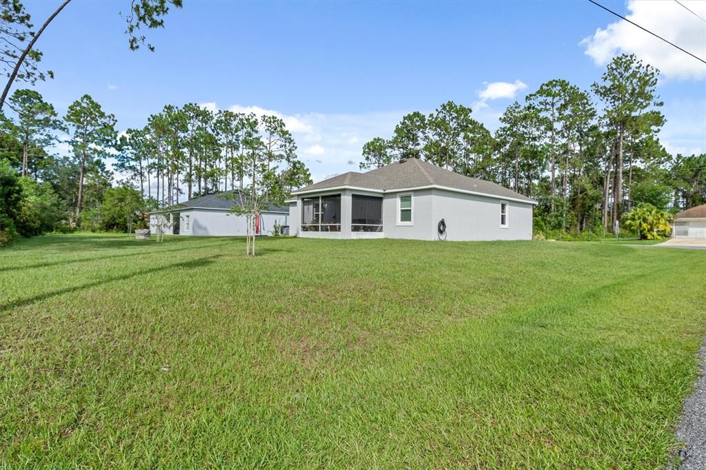 The exterior view shows the rear of a light-colored house with a screened-in porch — 5 BUD HOLLOW DRIVE, PALM COAST, FL