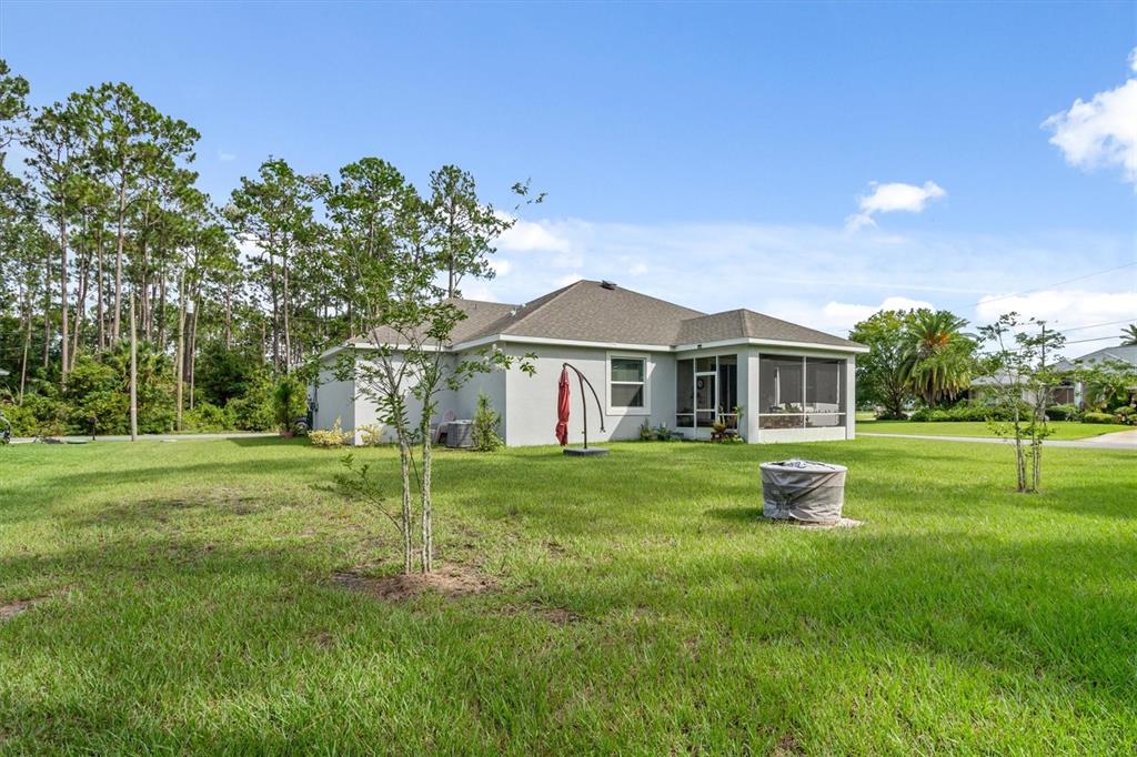 A single-story house with a screened-in porch sits on a large, grassy lawn — 5 BUD HOLLOW DRIVE, PALM COAST, FL