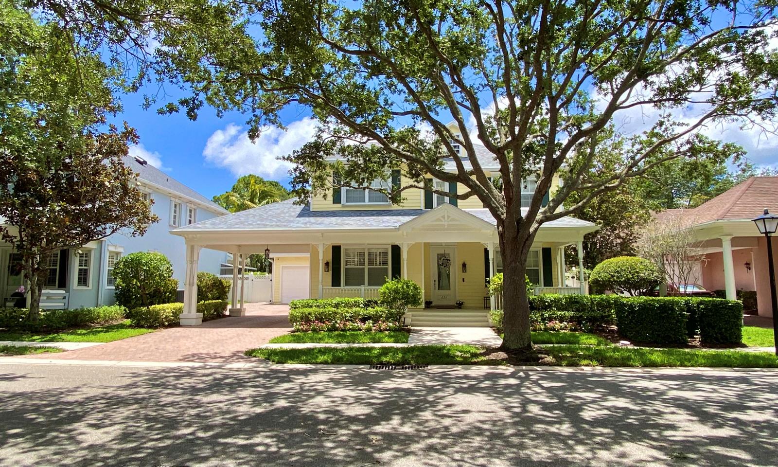 A yellow two-story house with a front porch, carport, and large tree in the yard — 221 Marlberry Circle, Jupiter FL 33458, JUPITER, FL
