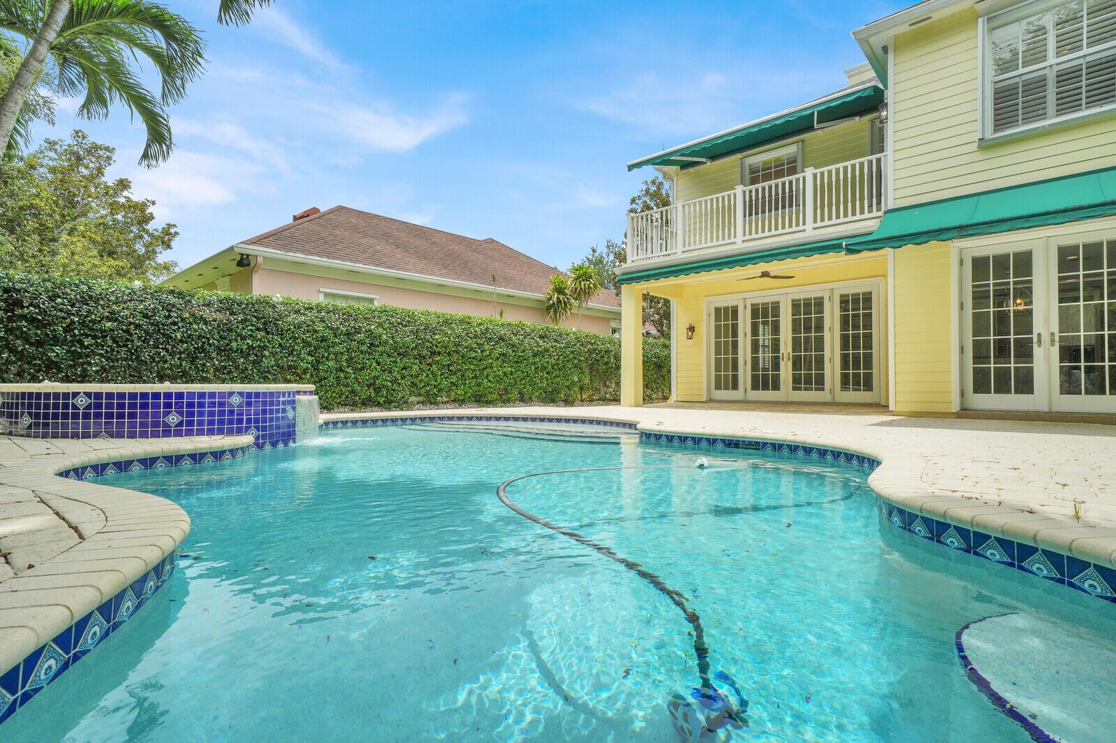 A yellow two-story house with a pool, spa, and green awnings in the backyard — 221 Marlberry Circle, Jupiter FL 33458, JUPITER, FL
