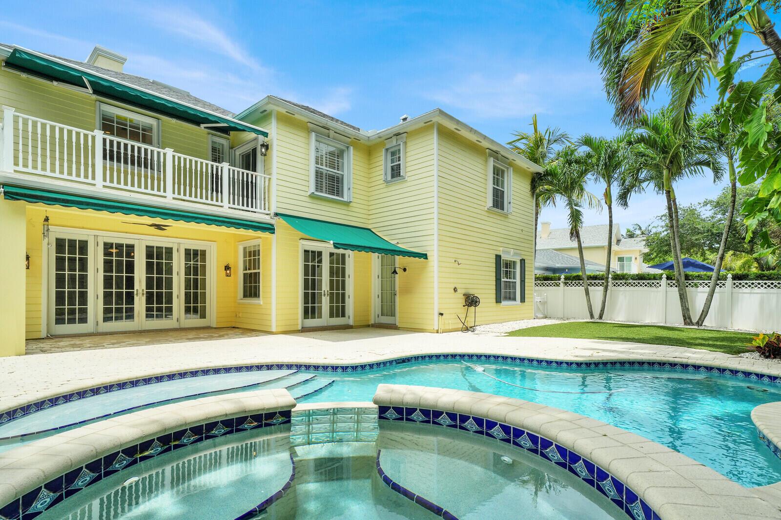 A two-story yellow house with a pool, hot tub, and green awnings in the backyard — 221 Marlberry Circle, Jupiter FL 33458, JUPITER, FL