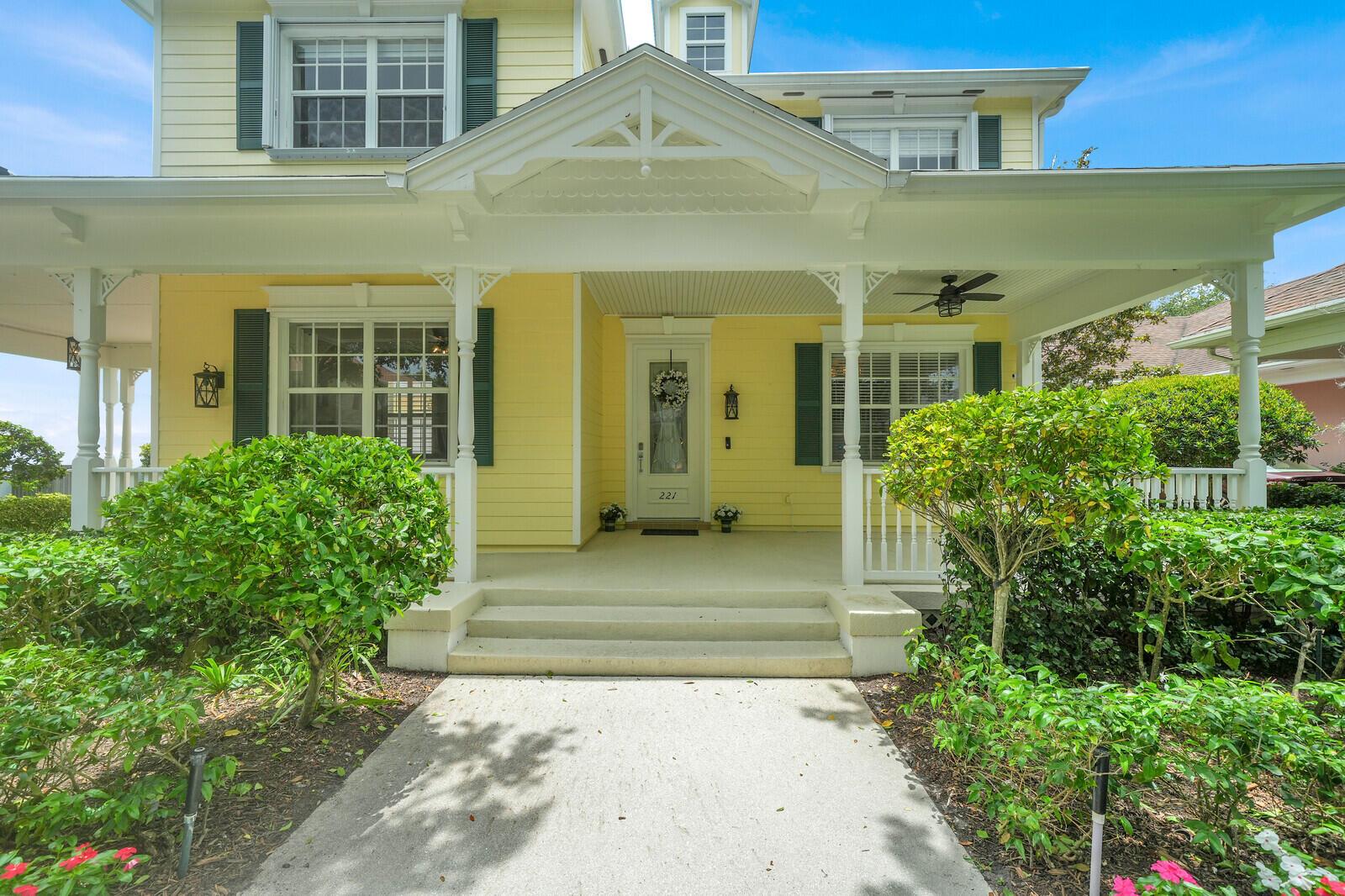 A yellow two-story house with a covered front porch, white railings, and a concrete walkway — 221 Marlberry Circle, Jupiter FL 33458, JUPITER, FL