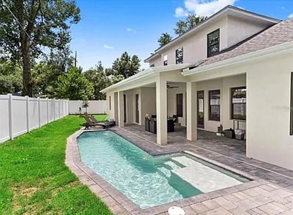 A backyard features a rectangular swimming pool with a tanning ledge next to a covered patio — 2234 HOWARD DRIVE, WINTER PARK, FL