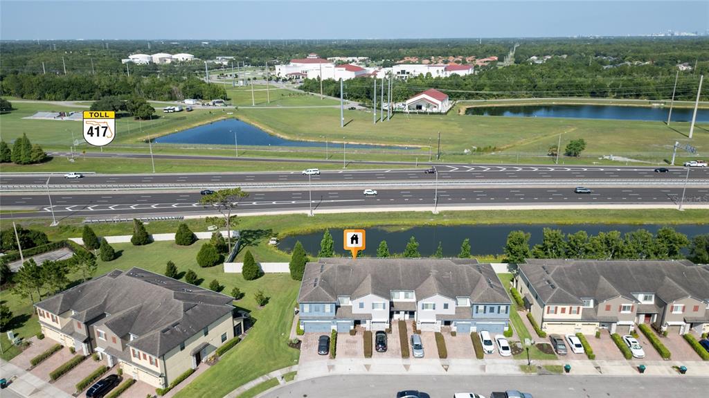 An aerial view shows a multi-unit townhouse complex situated near a highway and pond — 2840 WHITE ISLE LN, ORLANDO, FL
