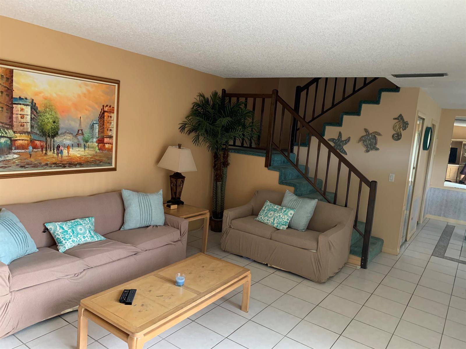 A living room features two tan sofas, a coffee table, and stairs with blue carpeting — 9403 S Ocean Drive # 3d, Jensen Beach FL 34957, JENSEN BEACH, FL