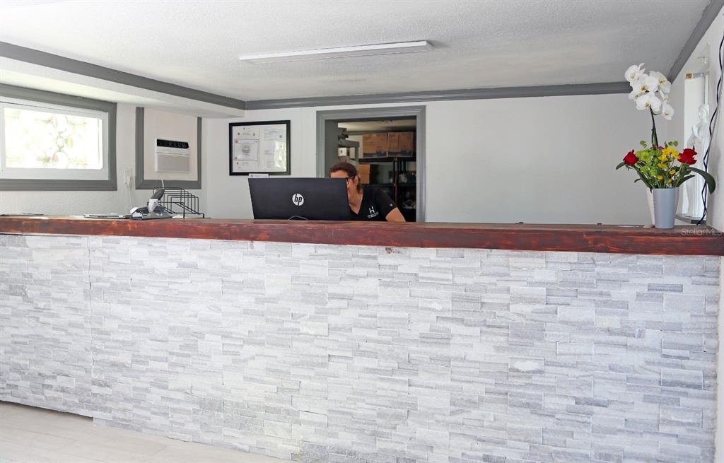 A reception desk with a stone facade and wood top sits in a bright office space — 14711 GULF BOULEVARD, MADEIRA BEACH, FL