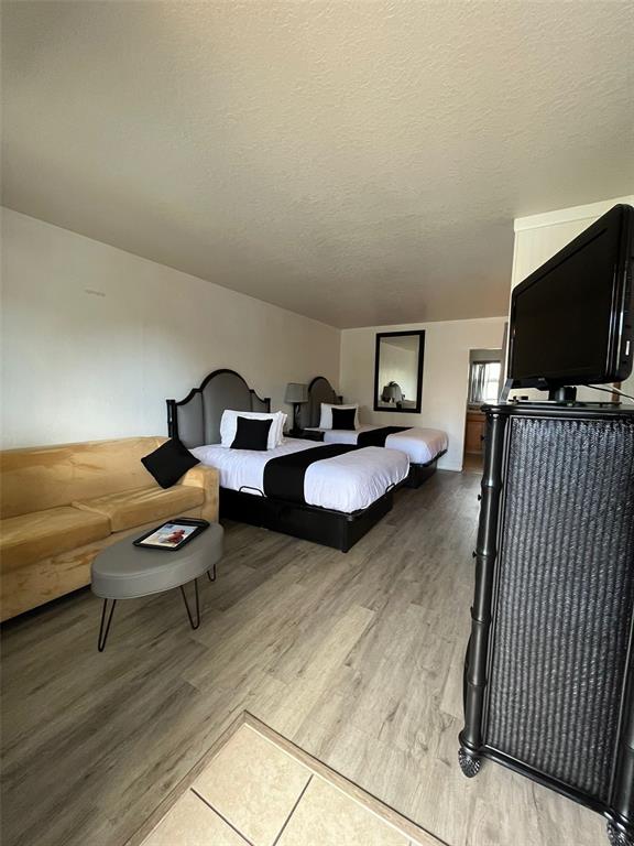 A hotel room features two beds, a tan sofa, a coffee table, and a television — 14711 GULF BOULEVARD, MADEIRA BEACH, FL