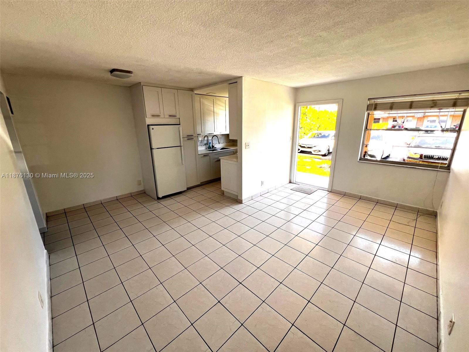 This room features white tile flooring, a small kitchen area, and a glass exterior door — 2145 Pierce St # 105, Hollywood FL 33020, HOLLYWOOD, FL