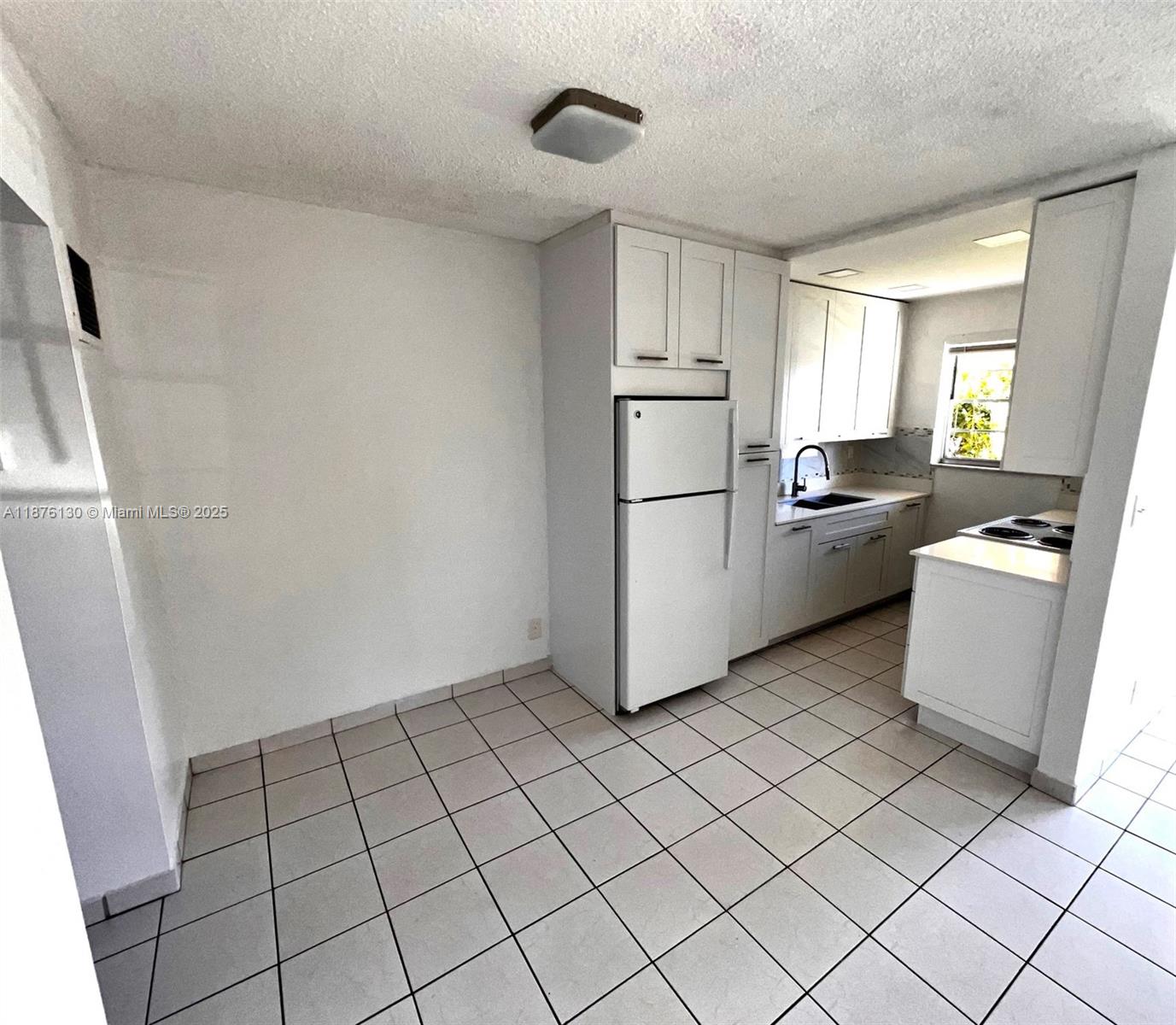 A kitchen features white cabinets, a white refrigerator, and light-colored square floor tiles — 2145 Pierce St # 105, Hollywood FL 33020, HOLLYWOOD, FL