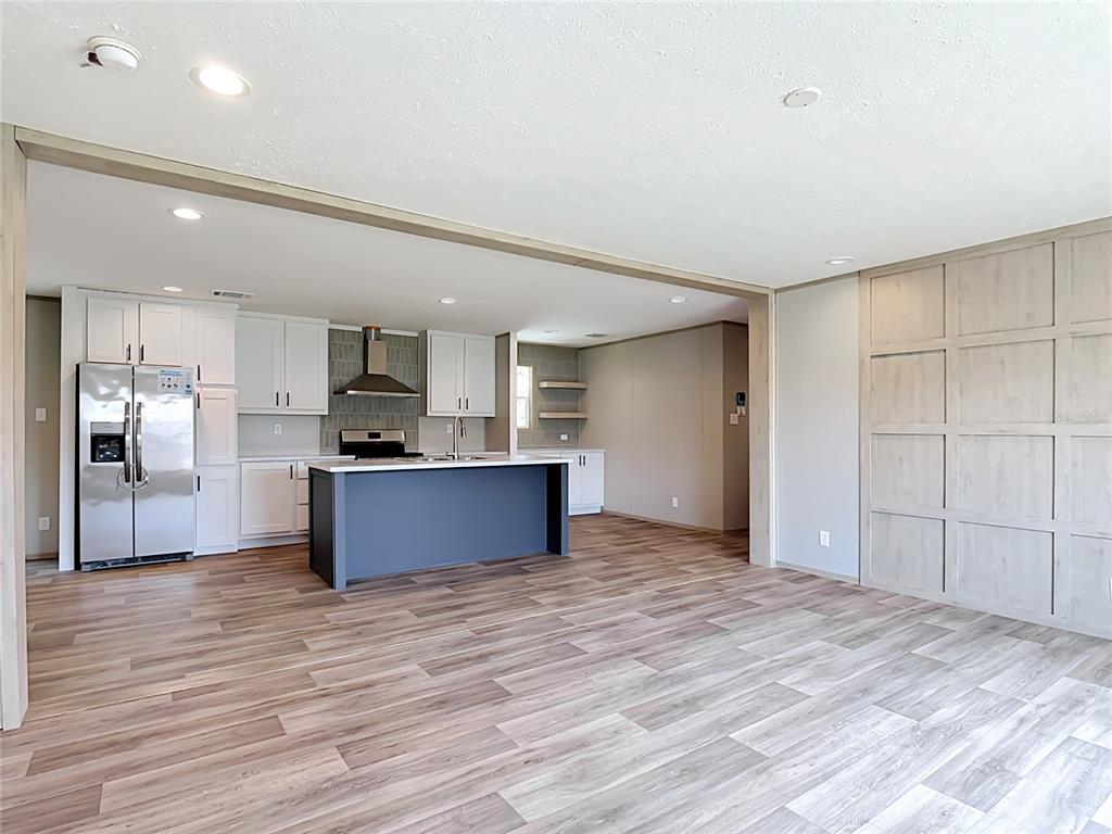 A kitchen with a blue island, white cabinets, and wood-look flooring opens to a living area — 1626 TARPON BOULEVARD, ST CLOUD, FL