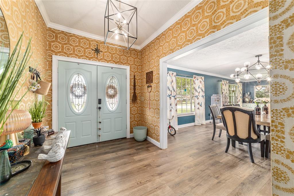 An entryway with light blue double doors and yellow patterned wallpaper leads into a dining room — 1308 SE 18TH STREET, OCALA, FL