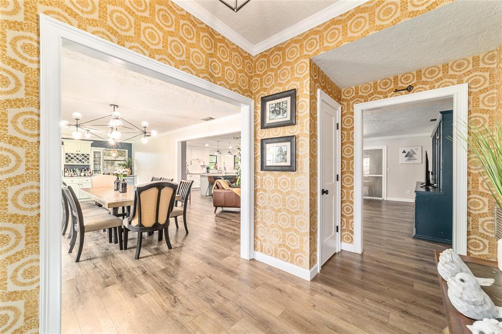 A hallway with patterned yellow wallpaper leads into a dining room and an adjacent living area — 1308 SE 18TH STREET, OCALA, FL