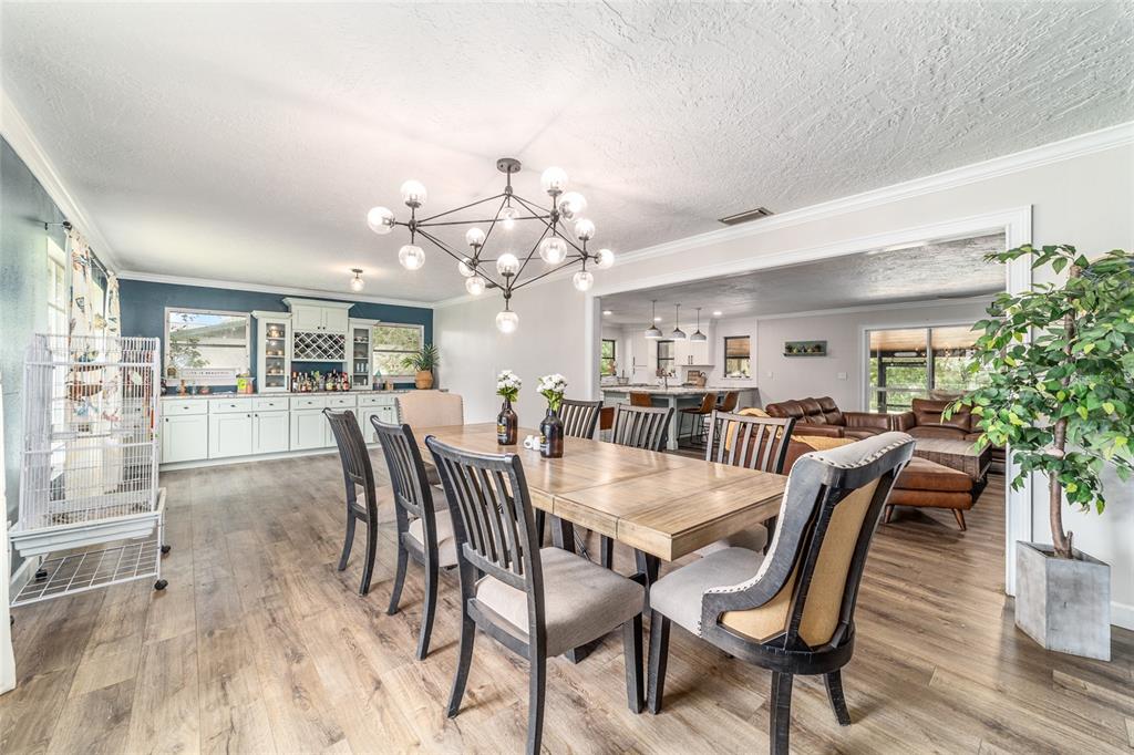 A dining room with a modern chandelier, wooden table, and an adjacent open-concept kitchen — 1308 SE 18TH STREET, OCALA, FL
