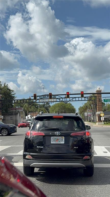 A black Toyota RAV4 sits at a traffic light under a historic downtown archway — 1121 N MAIN STREET, KISSIMMEE, FL