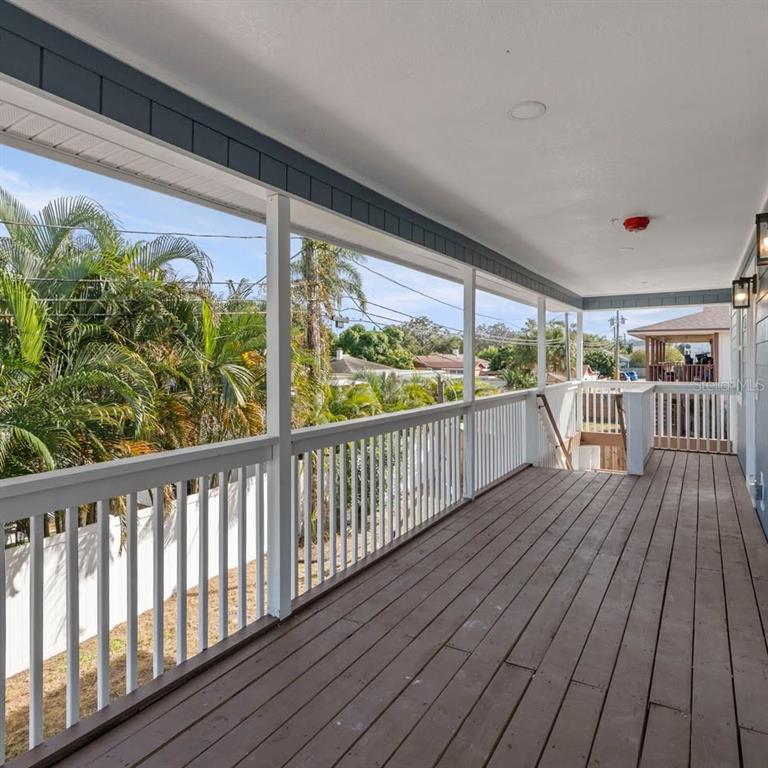 A long, covered wooden deck features white railings and views of palm trees and houses — 3107 16TH STREET N, ST PETERSBURG, FL
