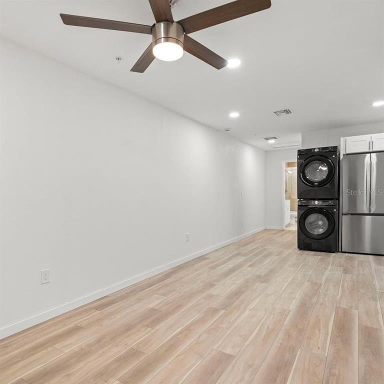 A room with light wood-look flooring, a ceiling fan, and a stacked washer and dryer — 3107 16TH STREET N, ST PETERSBURG, FL
