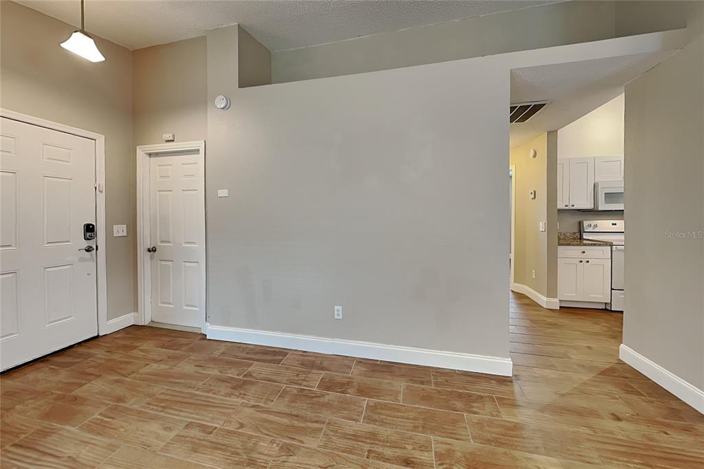 A view of an entryway with tile flooring, a white door, and an adjacent kitchen — 310 DIAMOND RIDGE BOULEVARD, AUBURNDALE, FL