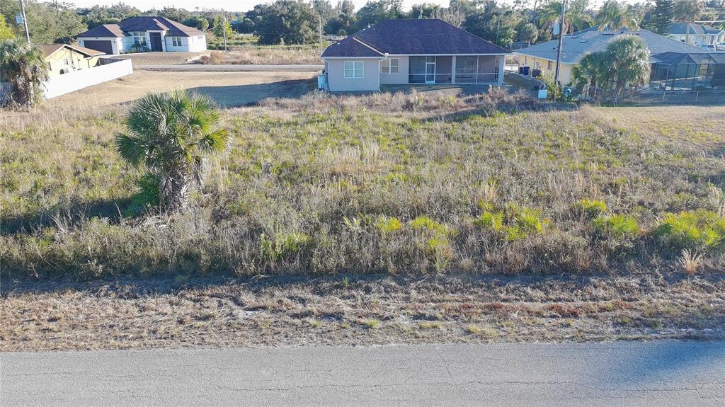 An elevated view shows a vacant, overgrown residential lot situated between two existing houses — Lots 22 & 23 LORANZA AVENUE, NORTH PORT, FL