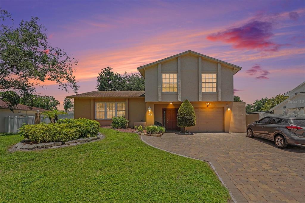 A two-story house with a paved driveway, a front lawn, and a sunset sky — 8206 VASSAR CIR, TAMPA, FL