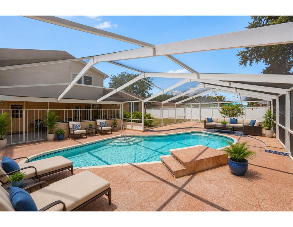 A screened-in patio features a swimming pool, lounge chairs, and outdoor seating — 8206 VASSAR CIR, TAMPA, FL