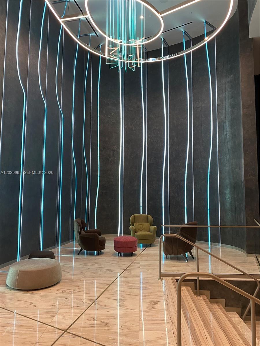 A modern lobby features a high ceiling with a circular light fixture and vertical light strips — 1000 Brickell Plz # 3412, Miami FL 33131, MIAMI, FL
