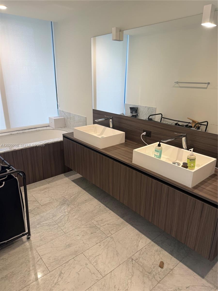 A modern bathroom features a floating wood vanity with two vessel sinks and marble flooring — 1000 Brickell Plz # 3412, Miami FL 33131, MIAMI, FL