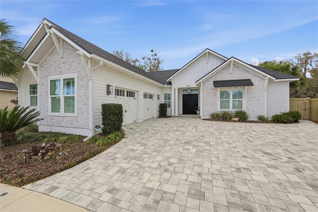 A single-story house with white stone and siding, a paver driveway, and a two-car garage — 1026 SW 120TH DRIVE, GAINESVILLE, FL