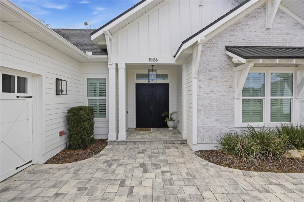 The exterior of a house features a paved walkway leading to a black double front door — 1026 SW 120TH DRIVE, GAINESVILLE, FL