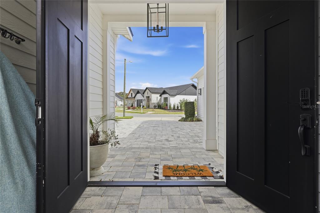 A view from an open doorway looking out onto a paved patio and neighborhood street — 1026 SW 120TH DRIVE, GAINESVILLE, FL