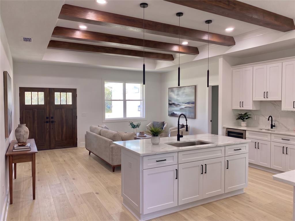 An open-concept kitchen and living area features white cabinetry, a marble island, and wood beams — 35425 NUTMEG DRIVE, WEBSTER, FL