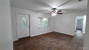 An empty living room features white walls, dark wood-look flooring, and a ceiling fan — 3214 DIAN ROAD, TALLAHASSEE, FL