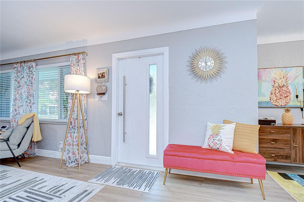 A bright entryway features a white door, a pink bench, and a sunburst wall clock — 130 63RD STREET S, ST PETERSBURG, FL