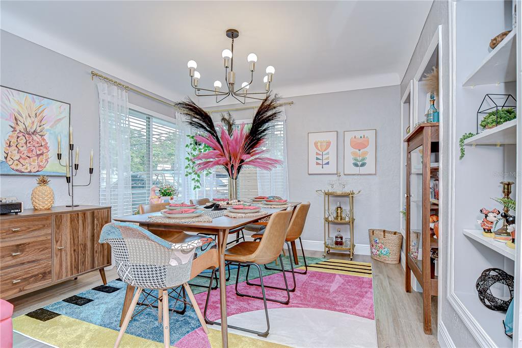 A dining room features a colorful geometric rug, a wooden table, and a modern chandelier — 130 63RD STREET S, ST PETERSBURG, FL
