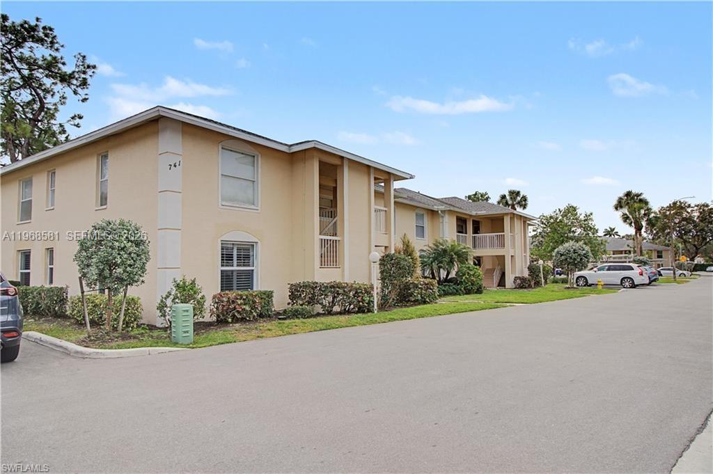 A two-story tan apartment building with a parking lot in the foreground — 741 Landover Cir # 102, Naples FL 34104, NAPLES, FL
