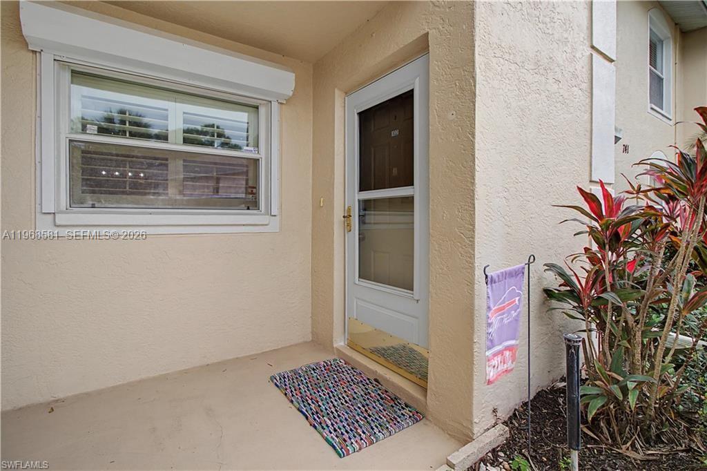 A beige exterior entryway features a white storm door, a window, and a colorful rug — 741 Landover Cir # 102, Naples FL 34104, NAPLES, FL