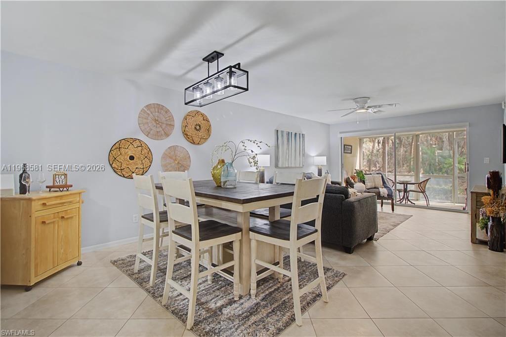 A dining area with a wooden table and chairs sits adjacent to a living room — 741 Landover Cir # 102, Naples FL 34104, NAPLES, FL