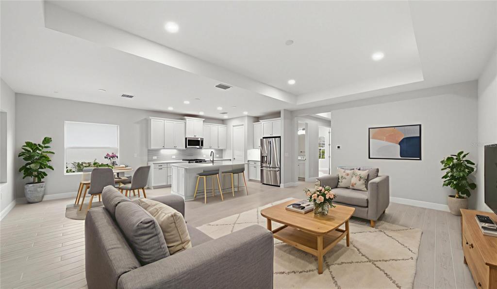 An open-concept living room and kitchen featuring white cabinetry, a central island, and light flooring — 3075 HERITAGE PINES DRIVE, FORT MYERS, FL