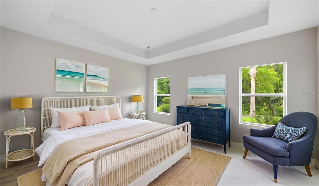 A bedroom features a white bed, a blue dresser, a blue armchair, and large windows — 3075 HERITAGE PINES DRIVE, FORT MYERS, FL