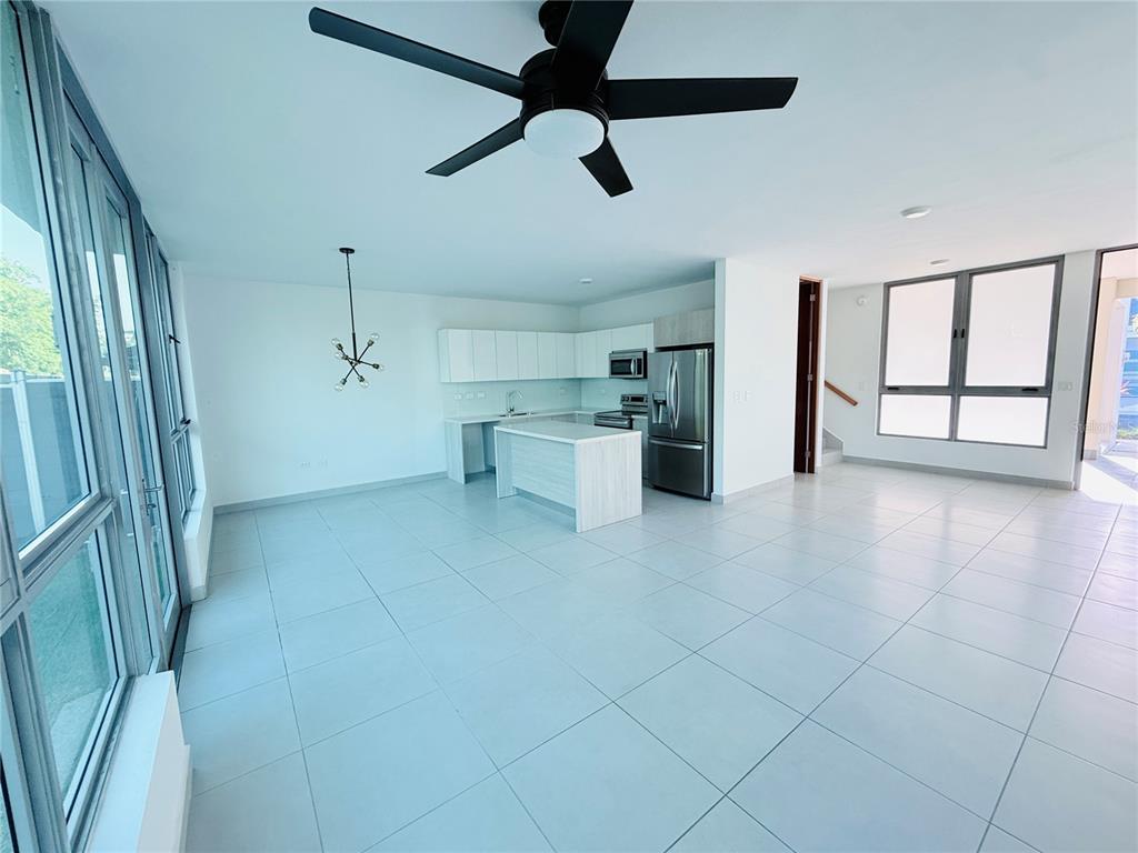 An open-concept kitchen and living area features white cabinetry, a center island, and tile flooring — Urb Riviera Court 57, BAYAMON, PR